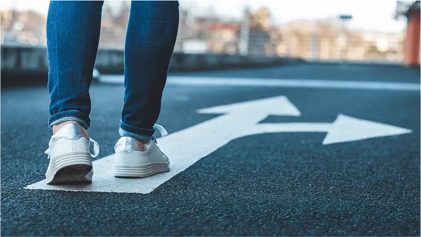 Pies caminando sobre flecha en la calzada