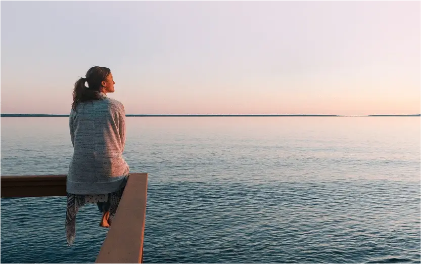 Chica contemplando el atardecer en el mar