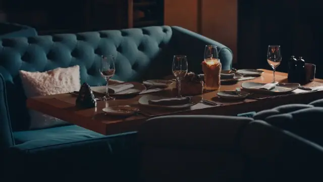  Mesa com talheres cuidadosamente organizados. Fundo de sofá com estilo barroco.